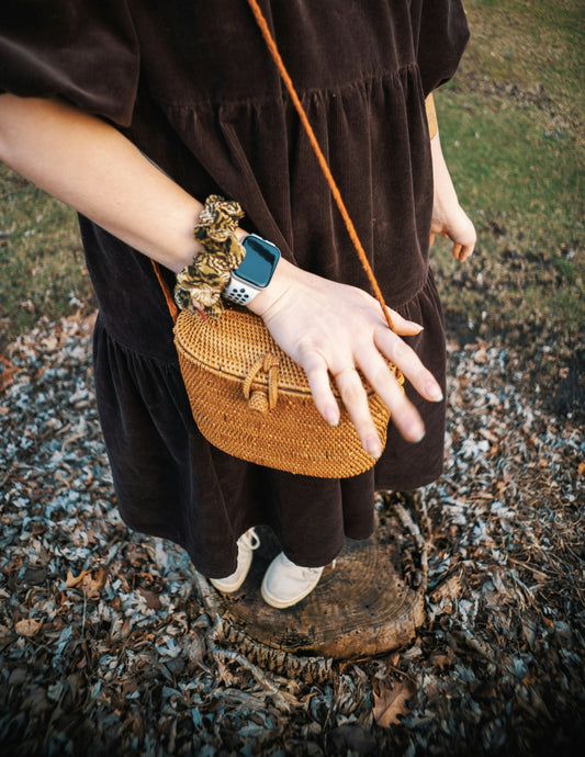 a woman in a brown dress holding a brown purse