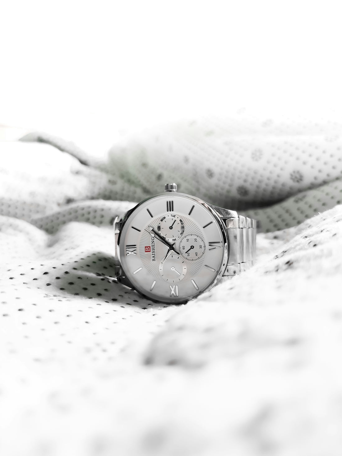 a watch sitting on top of a white blanket